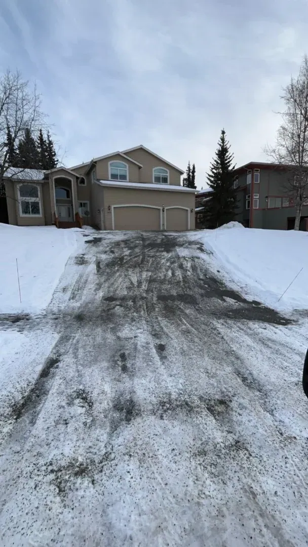 Driveway snow removal Anchorage Alaska - cleared path with snow-covered surroundings residential winter maintenance services