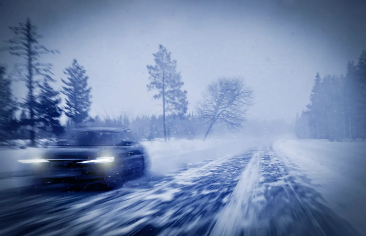 Snow removal services Anchorage Alaska - car driving through heavy snow on winter road demonstrating need for professional emergency snow plowing