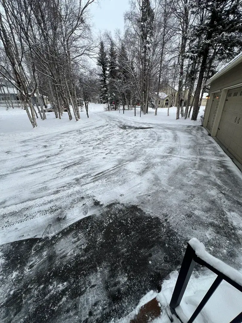 Professional snow clearing Anchorage Alaska - cleared residential driveway and walkway in snowy neighborhood with trees and homes